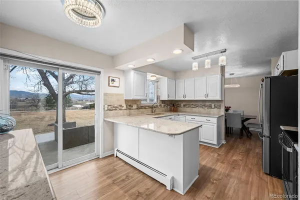 a kitchen with a refrigerator a sink dishwasher a stove and a dining table with wooden floor