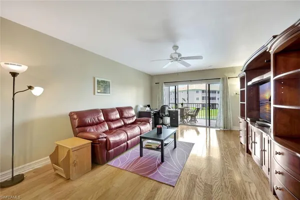 a living room with furniture a flat screen tv and a floor to ceiling window