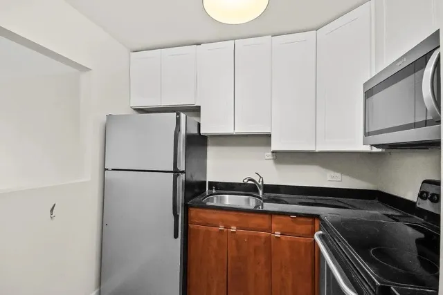 a kitchen with refrigerator a stove a sink and cabinets