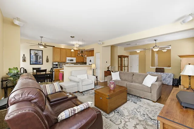 a living room with furniture kitchen view and a chandelier