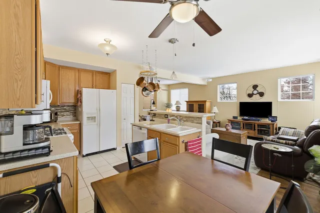 a living room with stainless steel appliances granite countertop furniture a fireplace a flat screen tv and a window