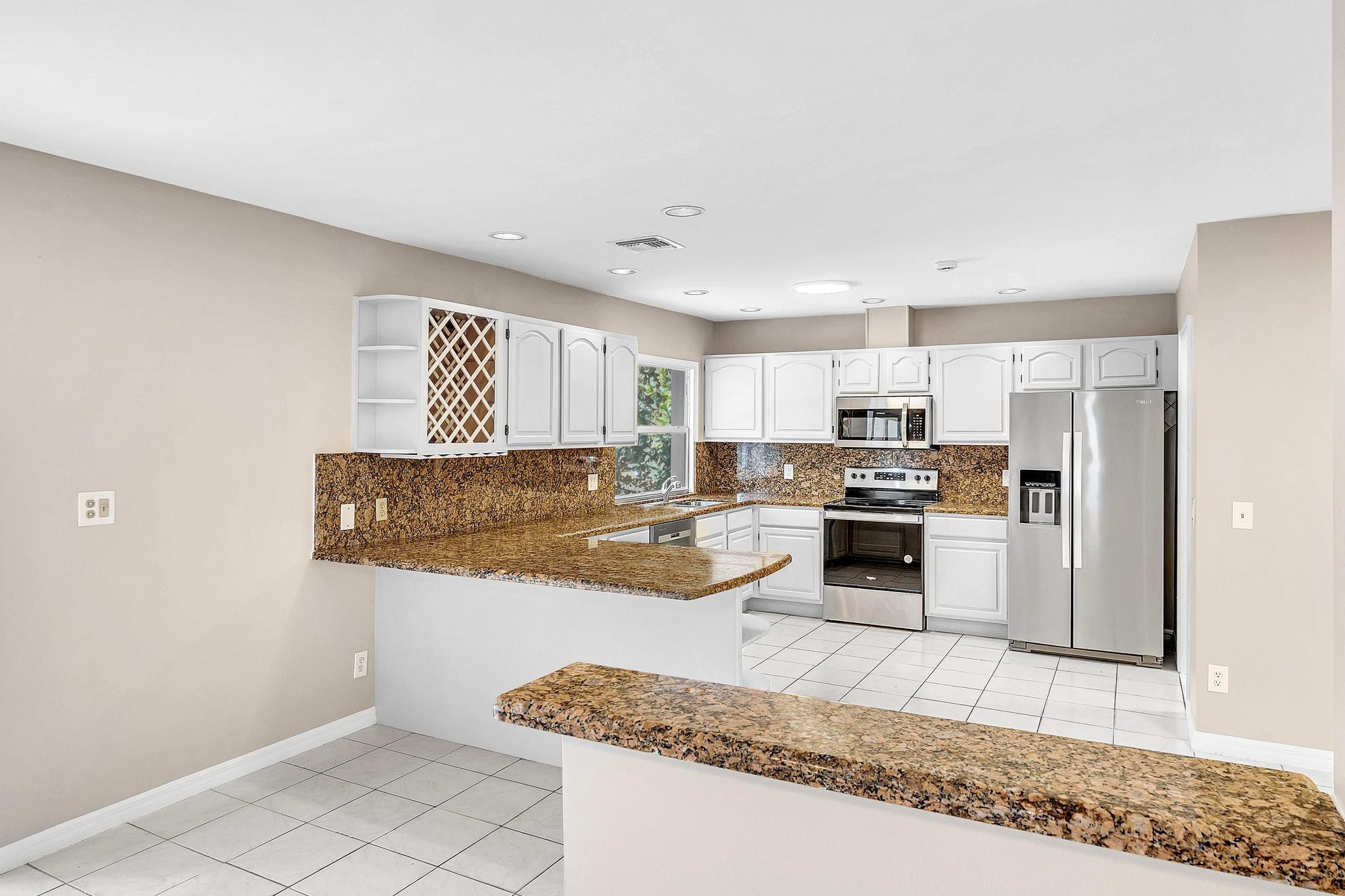 6144 Royal Lytham Drive Boca Raton, FL 33433 - Photo 15 of 70 a kitchen with stainless steel appliances granite countertop a refrigerator a stove and a sink