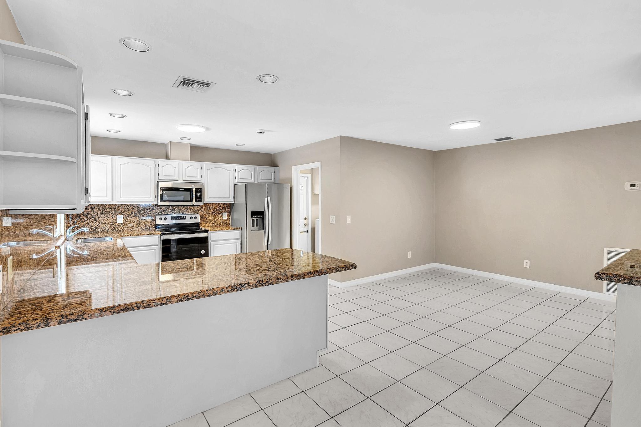 6144 Royal Lytham Drive Boca Raton, FL 33433 - Photo 16 of 70 a kitchen with granite countertop a sink and white cabinets