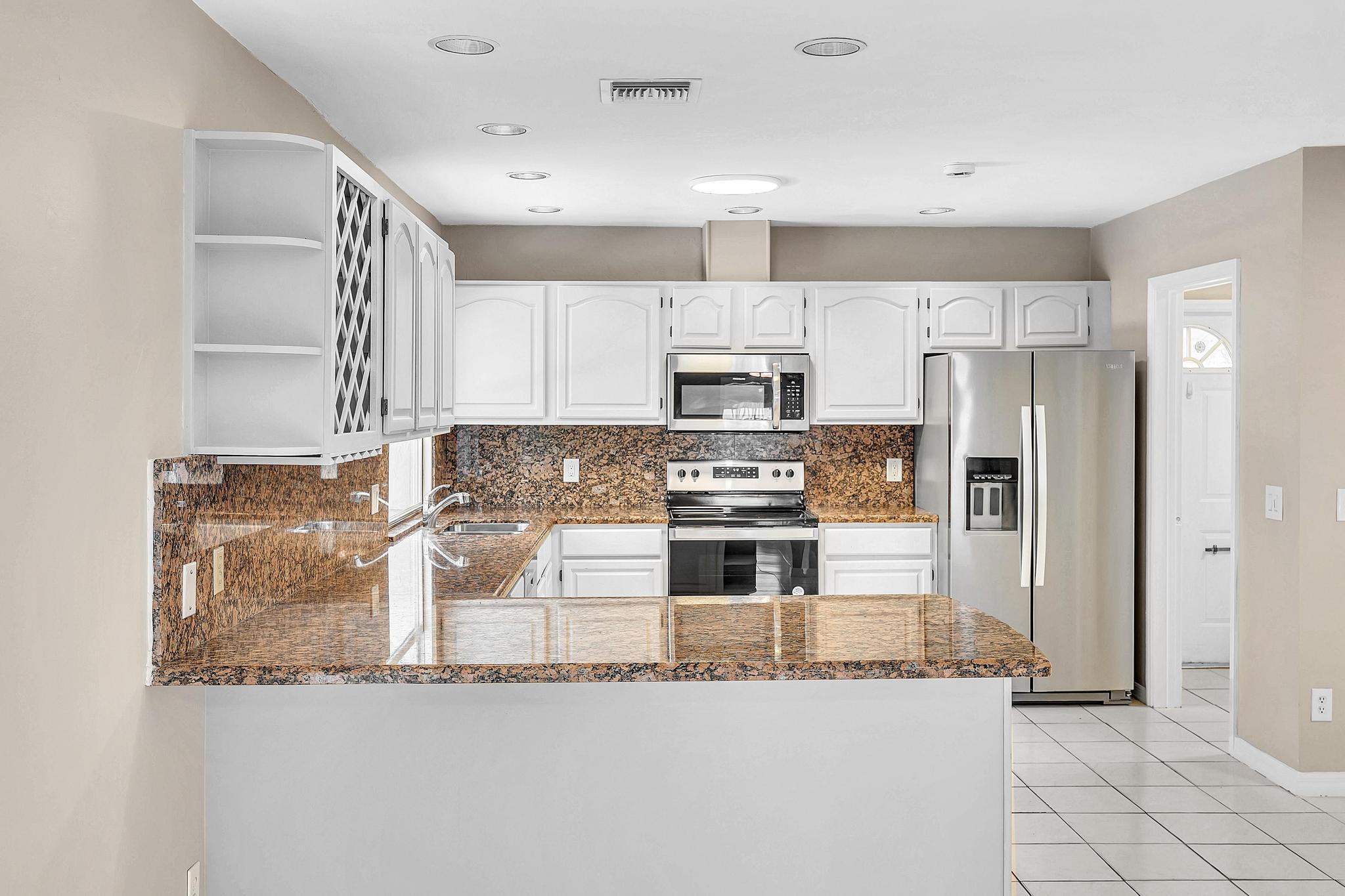 6144 Royal Lytham Drive Boca Raton, FL 33433 - Photo 17 of 70 a kitchen with granite countertop a refrigerator and a stove top oven