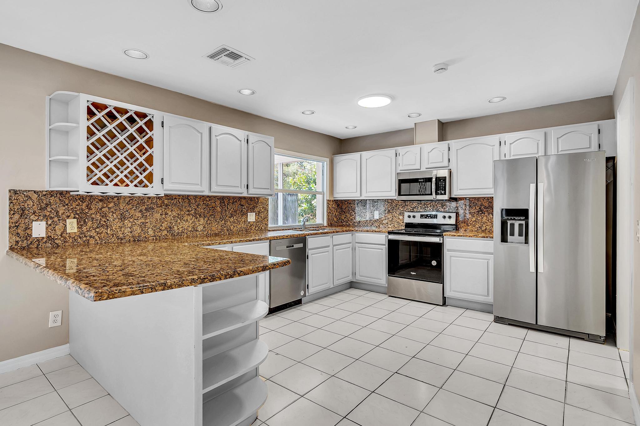 6144 Royal Lytham Drive Boca Raton, FL 33433 - Photo 21 of 70 a kitchen with granite countertop a refrigerator sink and cabinets