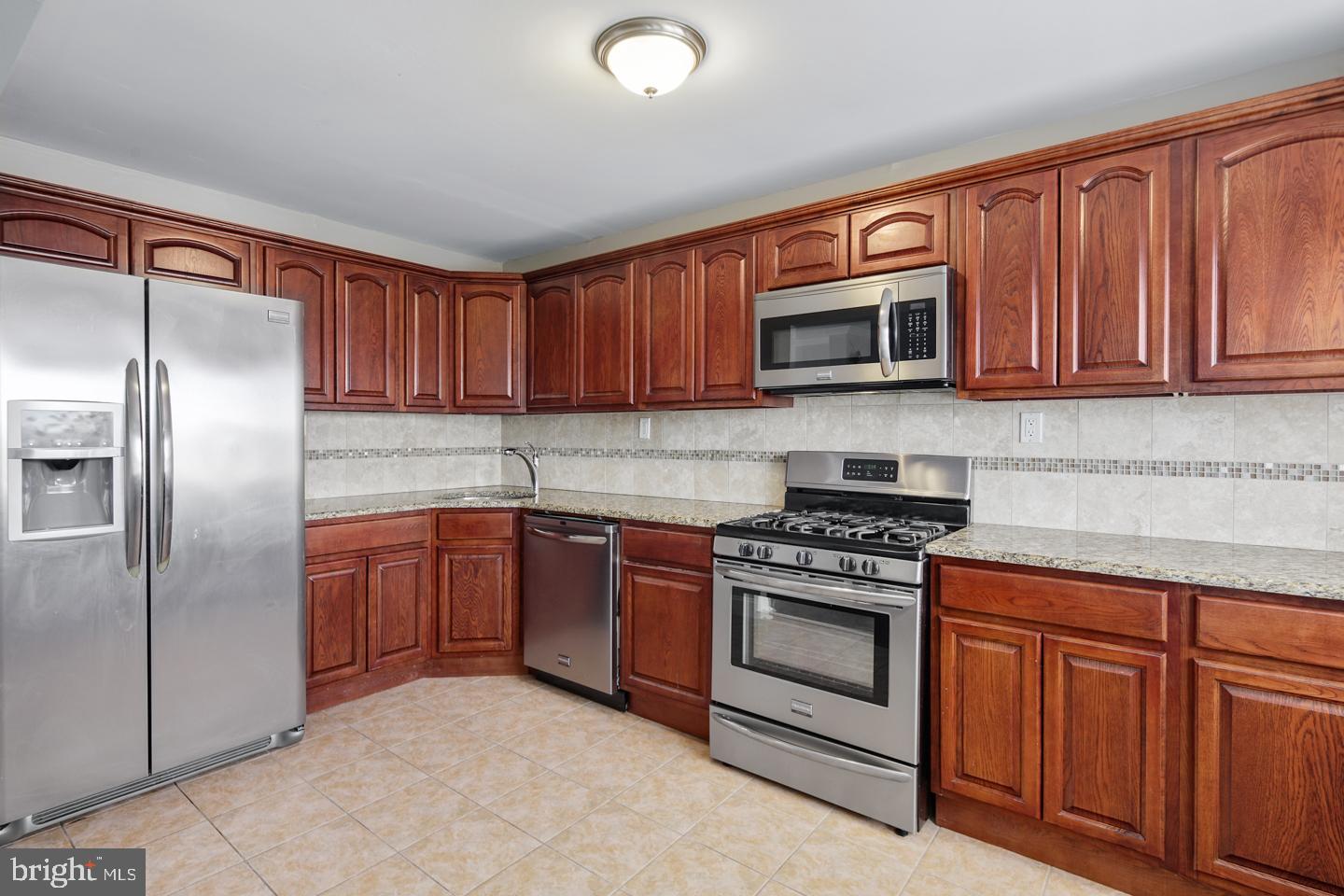 12519 Medford Road Philadelphia, PA 19154 - Photo 4 of 20 a kitchen with granite countertop wooden cabinets stainless steel appliances and a sink