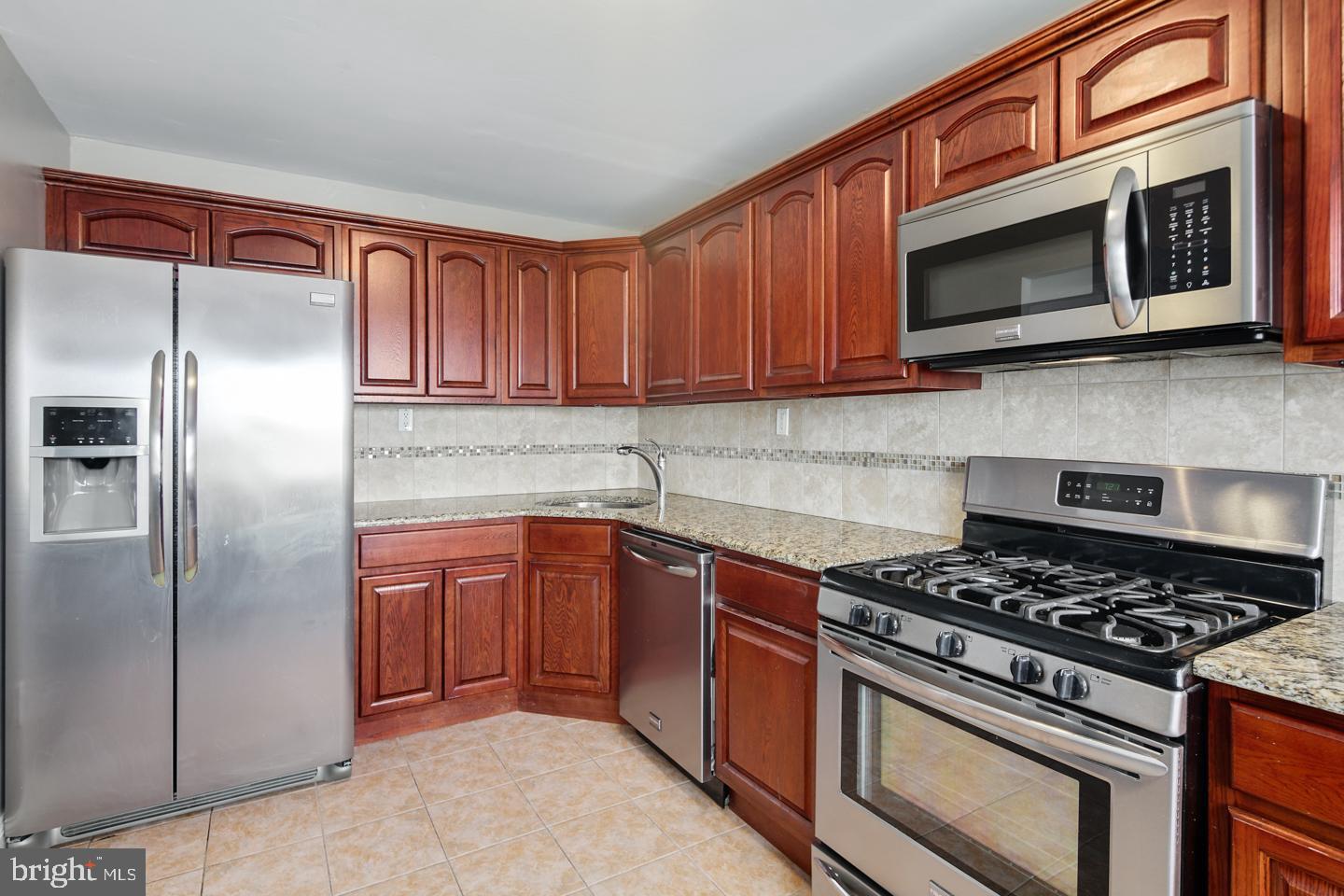 12519 Medford Road Philadelphia, PA 19154 - Photo 5 of 20 a kitchen with stainless steel appliances granite countertop a stove microwave and refrigerator