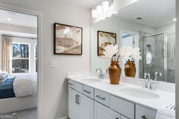 a bathroom with double vanity sinks a large mirror and a shower