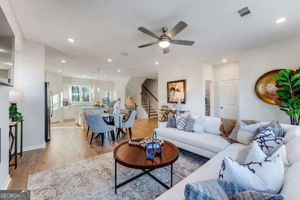 a living room with furniture kitchen view and a wooden floor