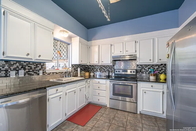 a kitchen with stainless steel appliances granite countertop a sink stove refrigerator and cabinets