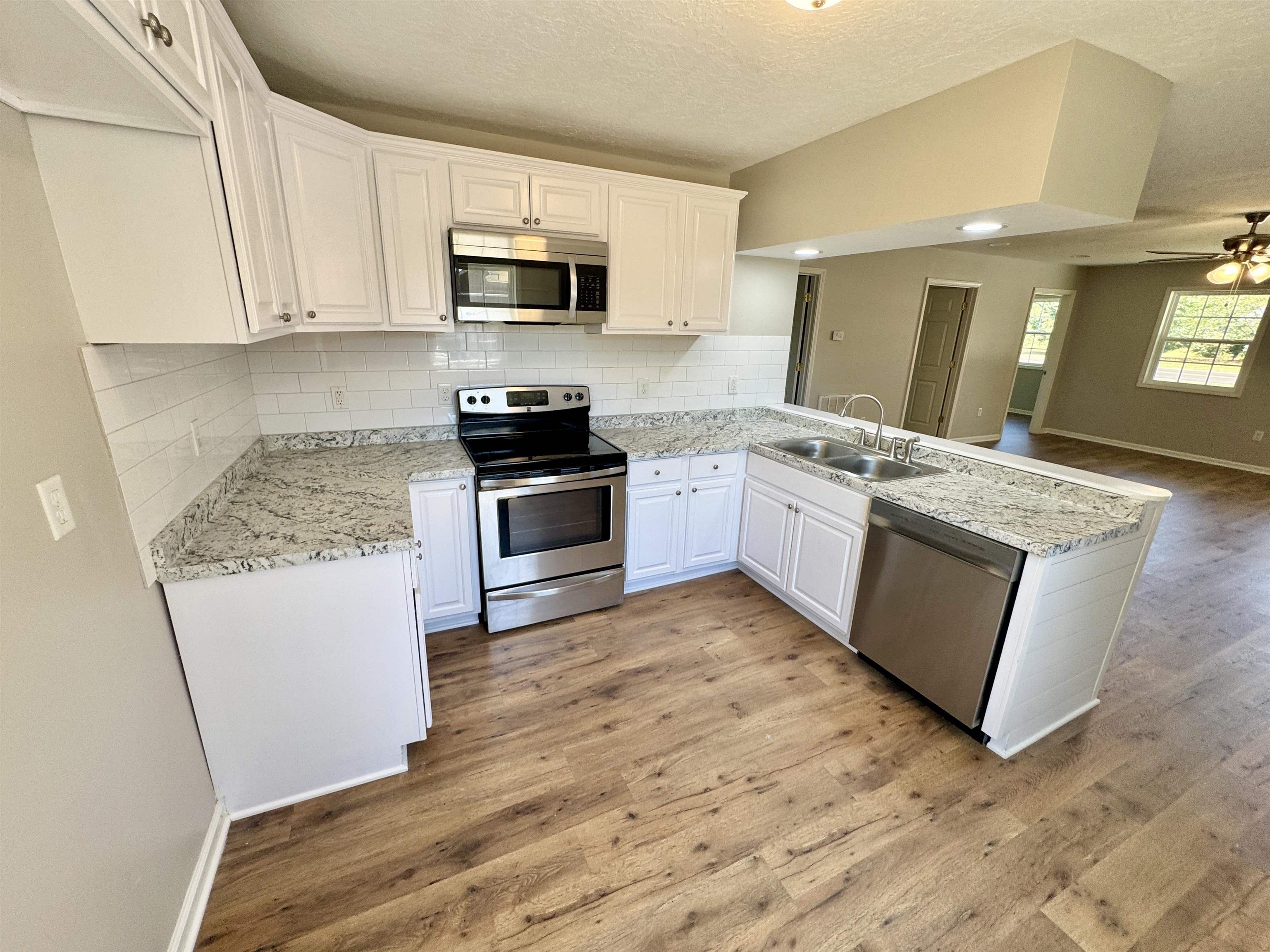 4638 Asbury Glimp Road Ripley, TN 38063 - Photo 7 of 16 a kitchen with stainless steel appliances granite countertop a stove top oven a sink a microwave and view living room