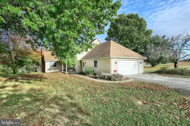 a view of a house with a yard and large tree