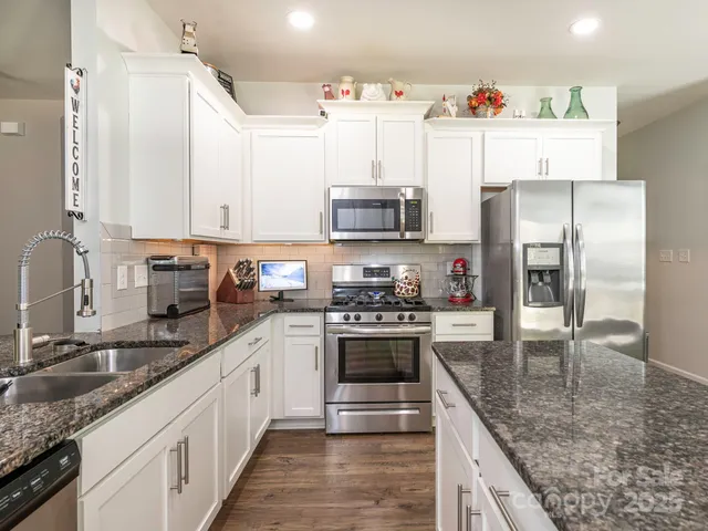 a kitchen with kitchen island granite countertop a sink stainless steel appliances and a counter space