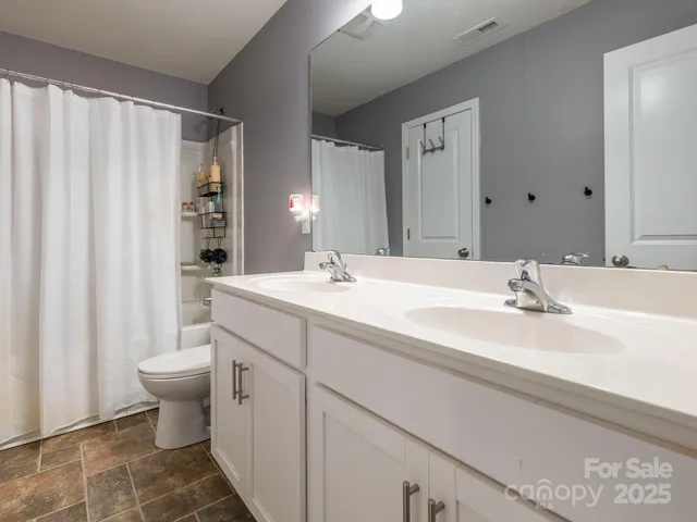 a bathroom with a double vanity sink toilet and a mirror