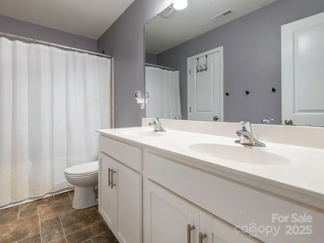 a bathroom with a double vanity sink toilet and a mirror