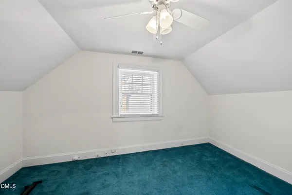 an empty room with a chandelier fan and windows