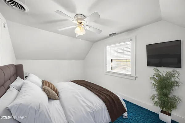 a bedroom with a bed tv and potted plant
