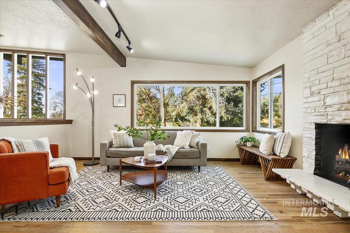 2518 Lancaster Drive Boise, ID 83702 - Photo 17 of 41 Living room featuring beamed ceiling, light wood-style floors, a stone fireplace, and track lighting