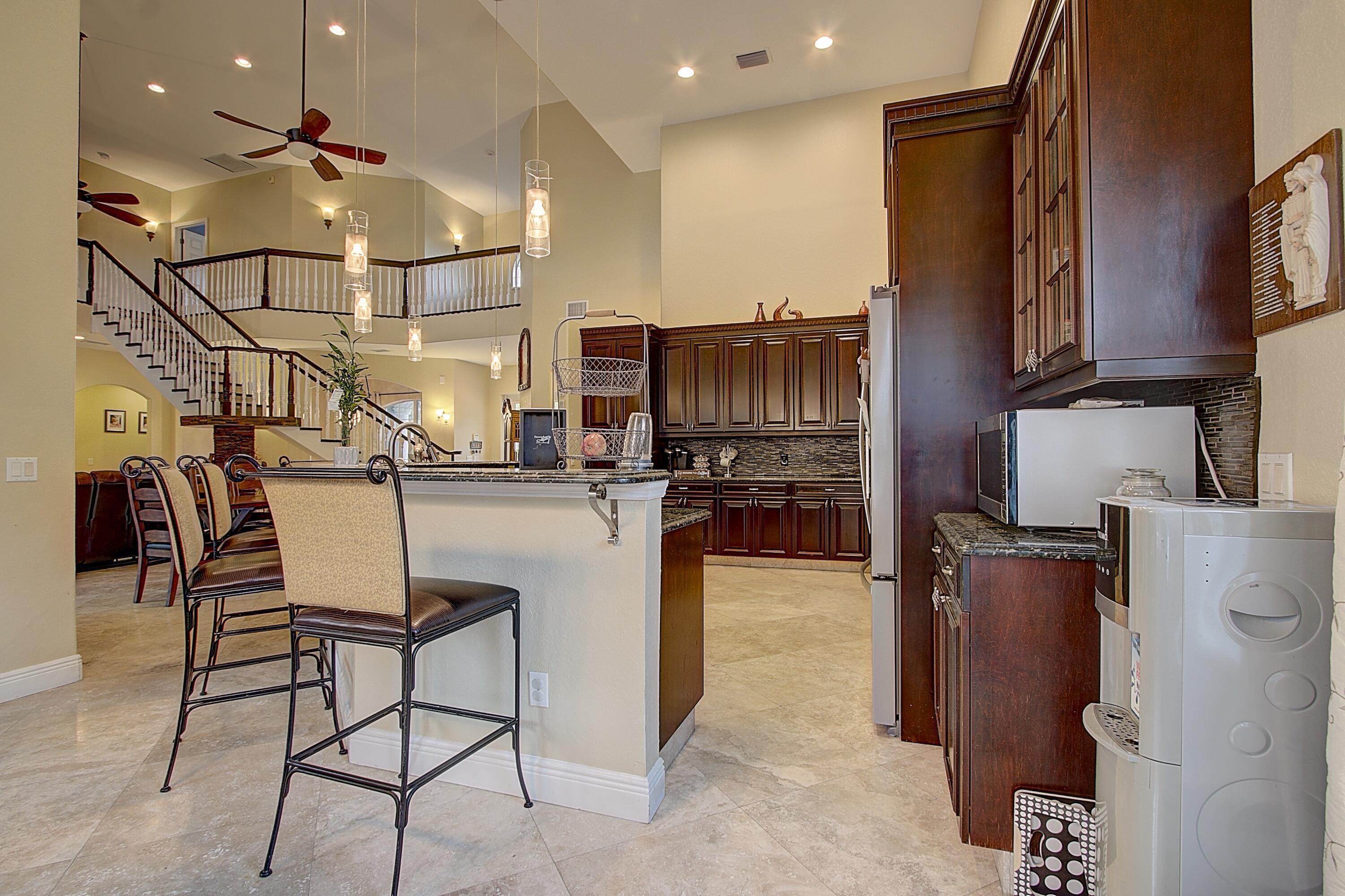 669 Howard Street Fort Pierce, FL 34982 - Photo 9 of 15 a kitchen with stainless steel appliances kitchen island granite countertop a refrigerator a stove and a sink with wooden floor