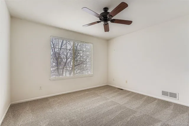 an empty room with a window and a fan