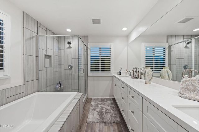 a spacious bathroom with a double vanity sink a mirror and a bathtub