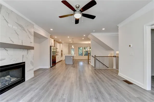 a view of an empty room and kitchen with fireplace ceiling fan