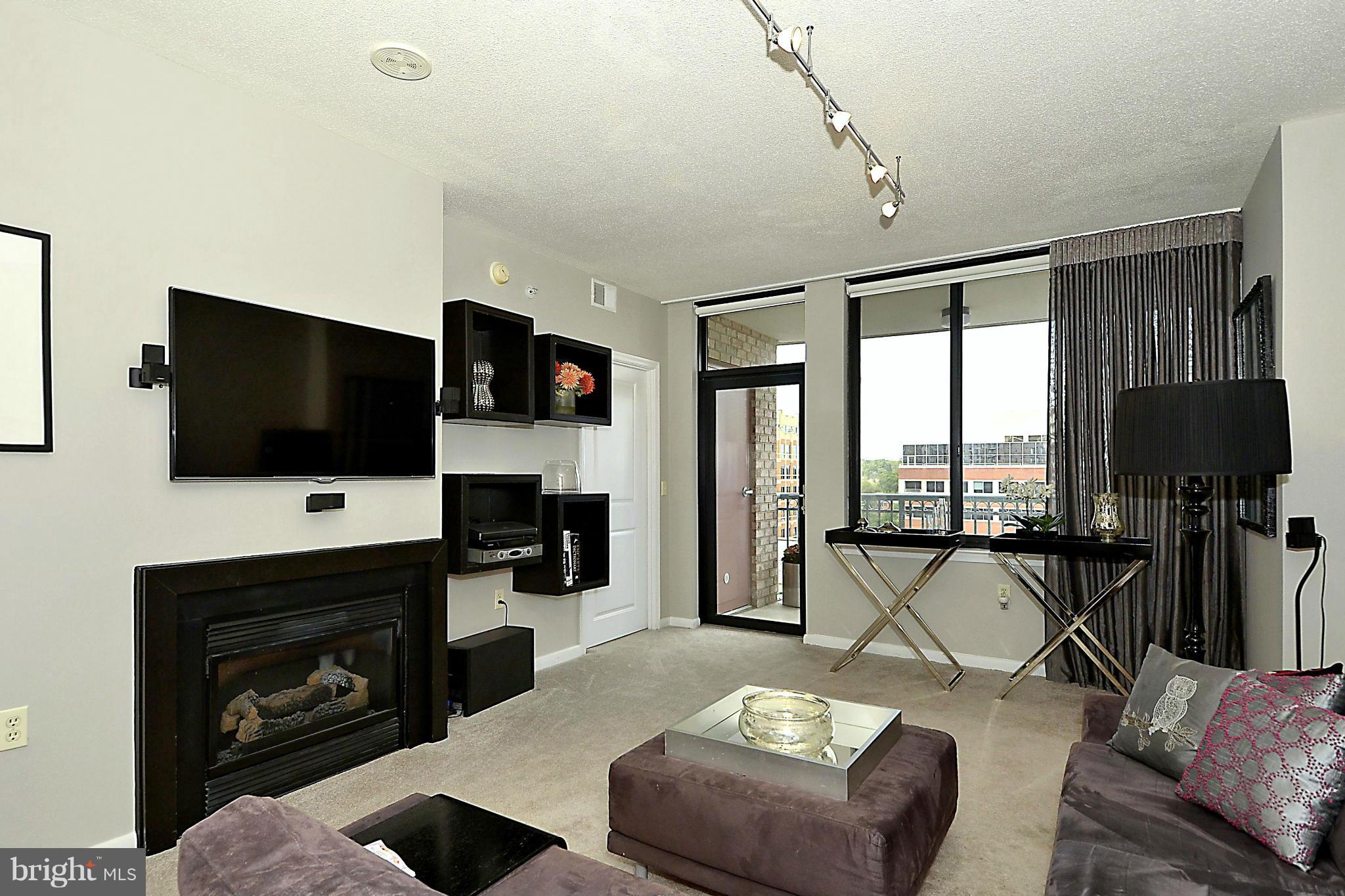 851 North Glebe Road, Unit 915 Arlington, VA 22203 - Photo 3 of 30 a living room with furniture a flat screen tv and a fireplace