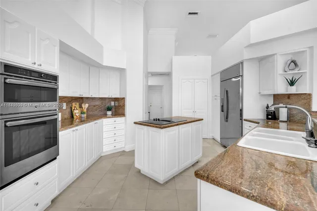 a kitchen with granite countertop kitchen island white cabinets and stainless steel appliances