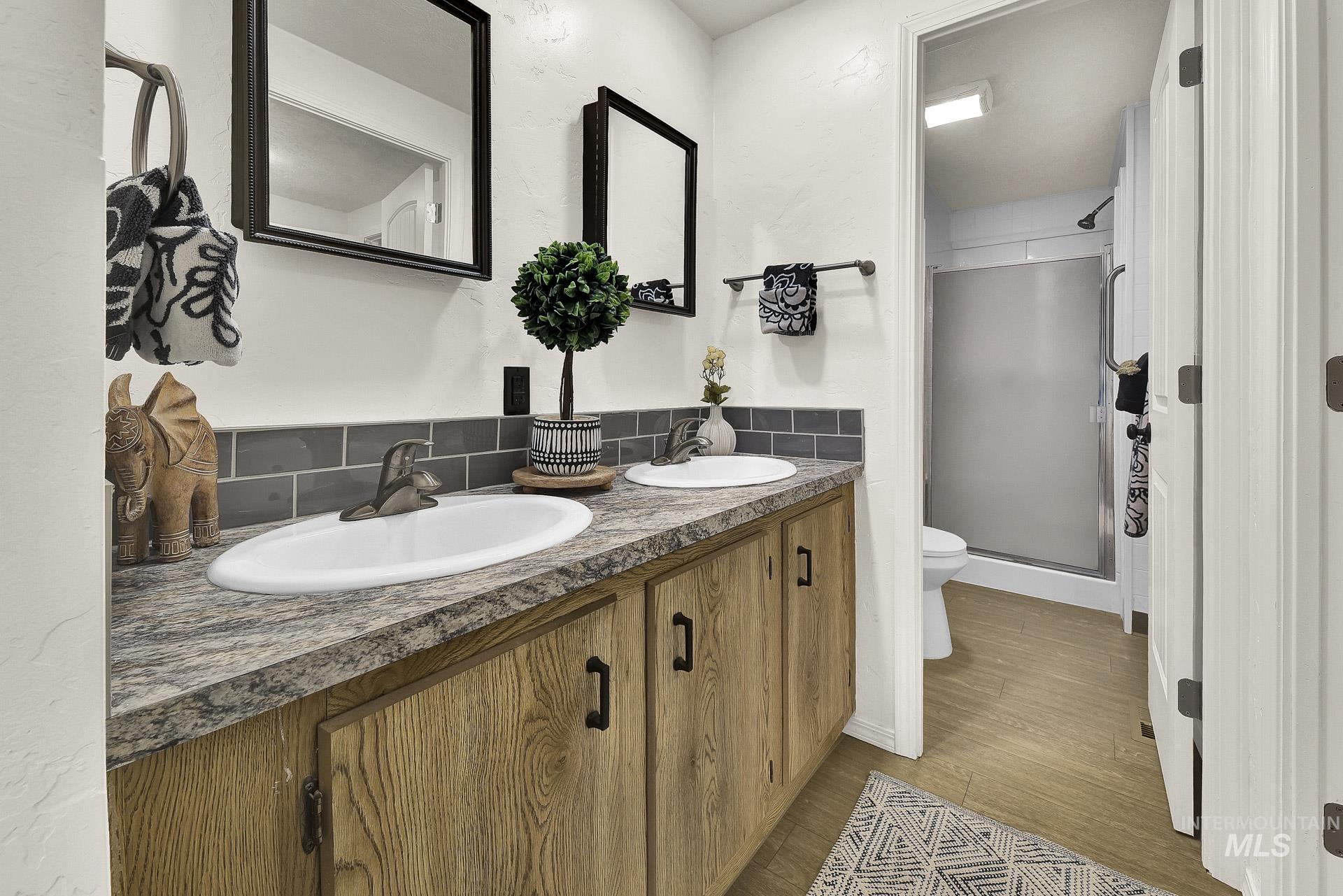 3249 Cherry Lane, Unit 23 Boise, ID 83705 - Photo 3 of 11 Full bath with a shower stall, double vanity, tasteful backsplash, and light wood-type flooring