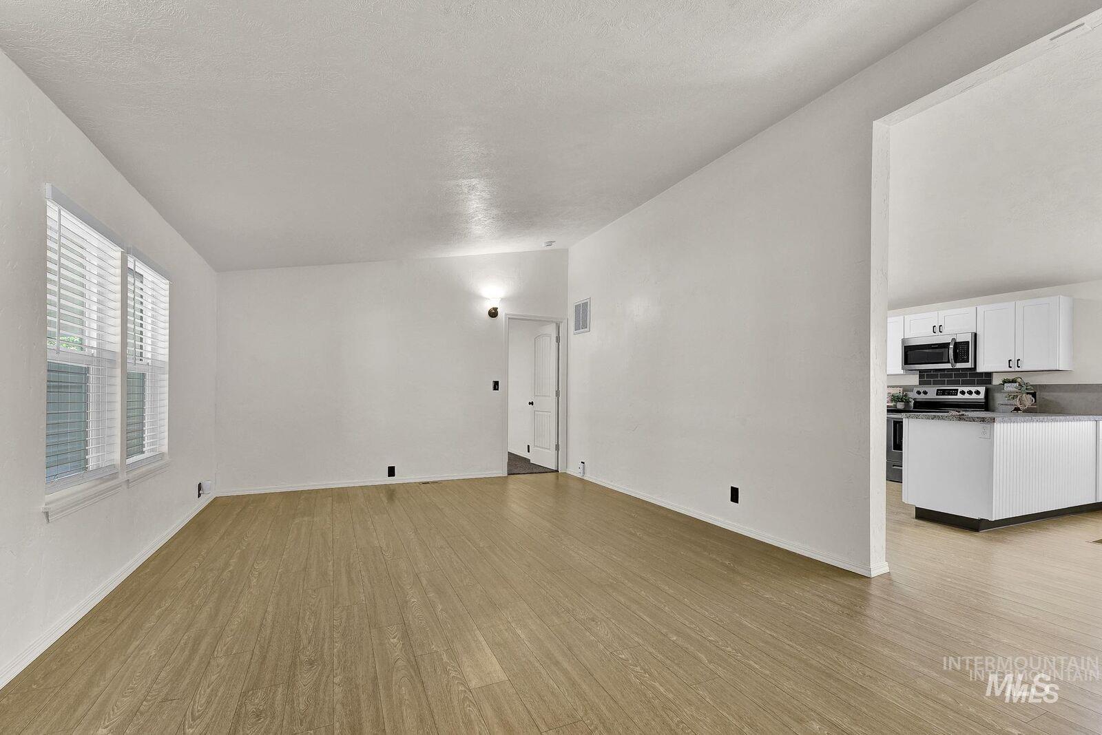 3249 Cherry Lane, Unit 23 Boise, ID 83705 - Photo 4 of 11 Empty room with vaulted ceiling, light wood finished floors, and a textured ceiling