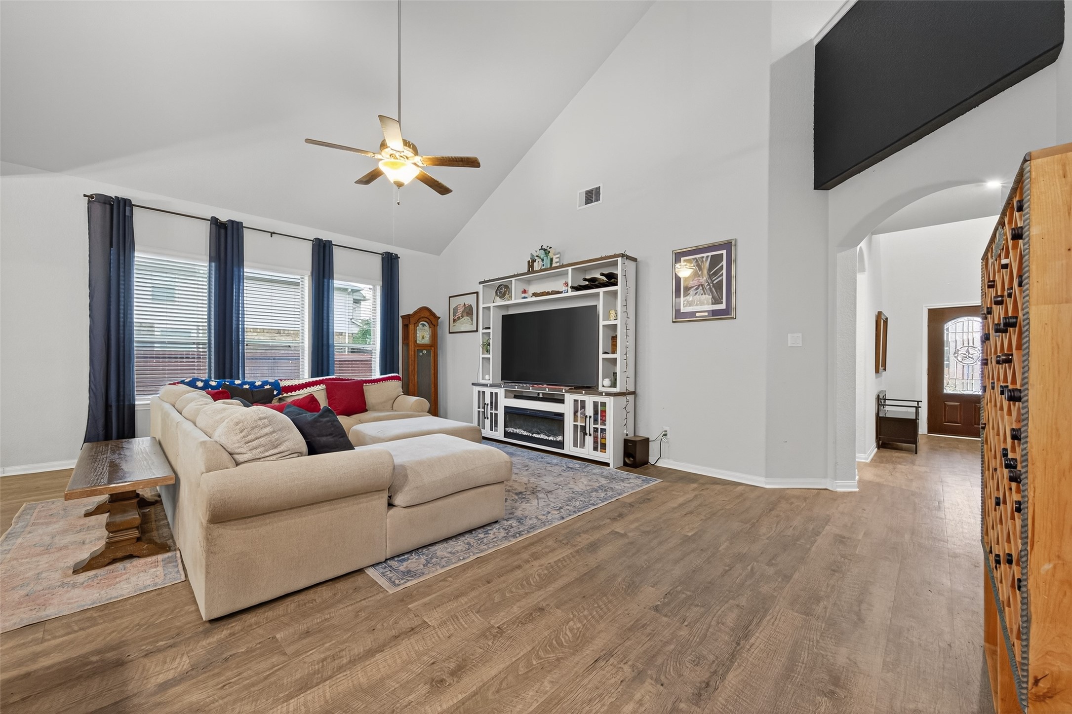 16601 Crosby Street Conroe, TX 77303 - Photo 16 of 50 Bright and spacious living room with soaring ceilings, large windows, and wood-look flooring—offering an open, inviting space perfect for relaxing or entertaining.