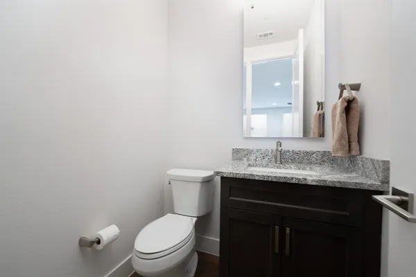 a bathroom with a granite countertop toilet sink and mirror