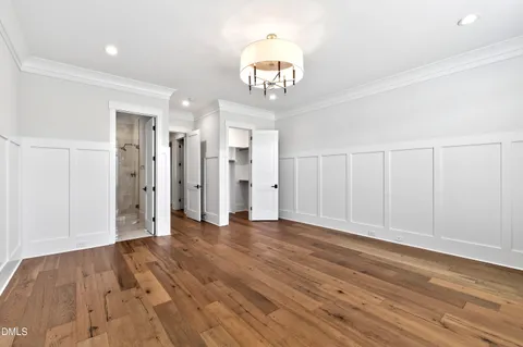 a view of an empty room with wooden floor and a ceiling fan