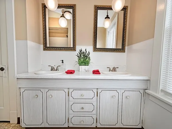 a bathroom with cabinets two sink a mirror and a window