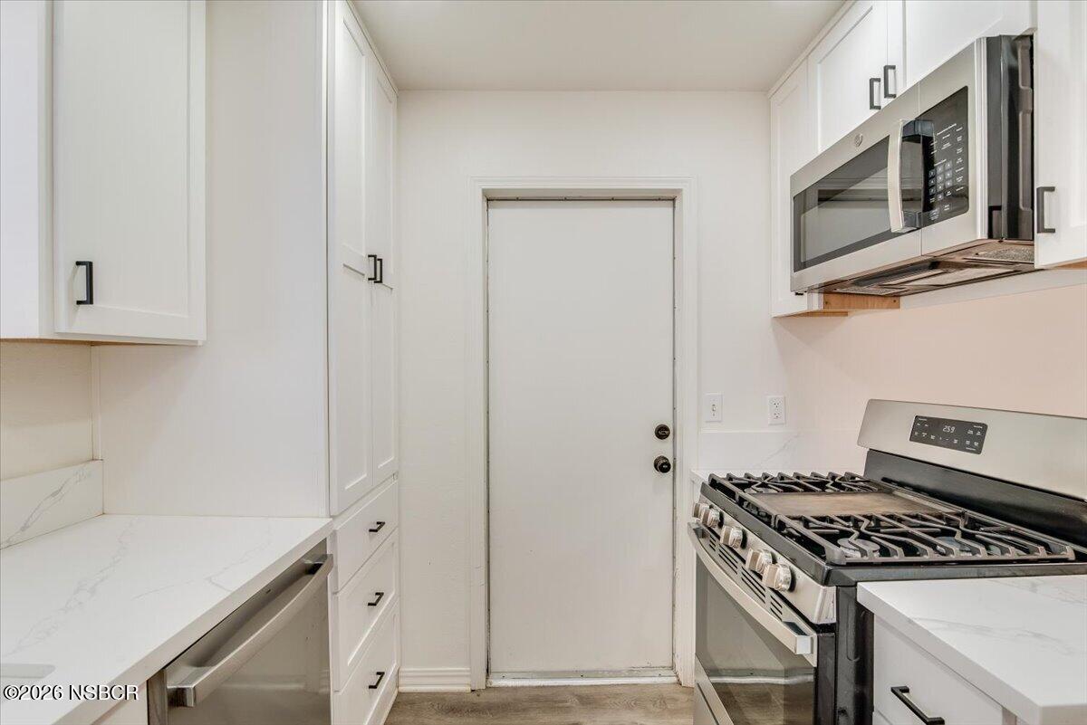 321 North Z Street Lompoc, CA 93436 - Photo 11 of 33 a kitchen with stainless steel appliances granite countertop white cabinets and black stove top oven with granite countertops