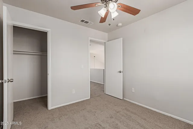 an empty room with a chandelier fan and closet area