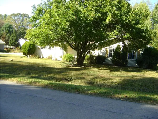 a view of a swimming pool with a yard and large trees