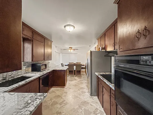 a kitchen with stainless steel appliances kitchen island granite countertop a sink stove and refrigerator