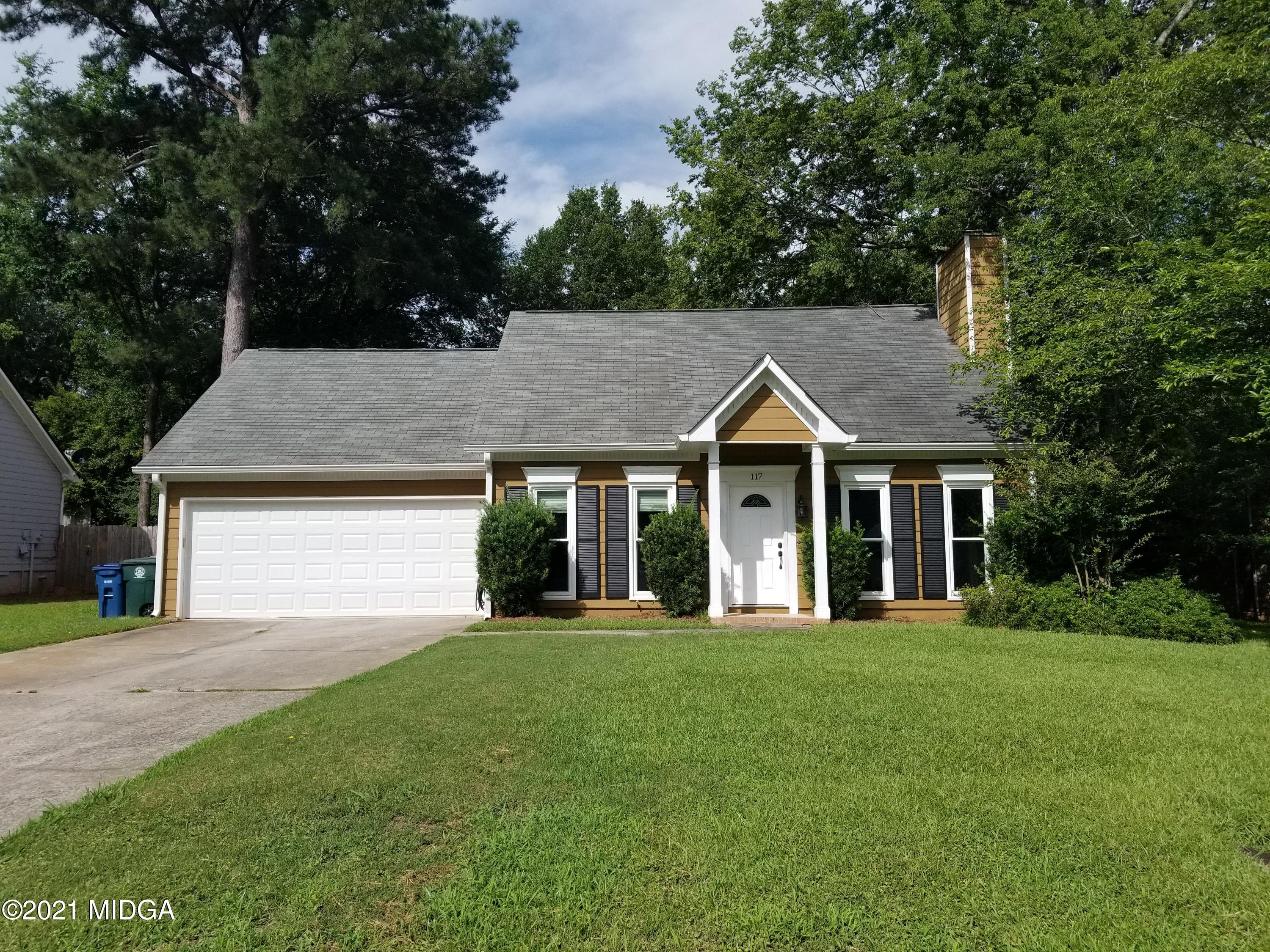 a front view of a house with a yard and trees