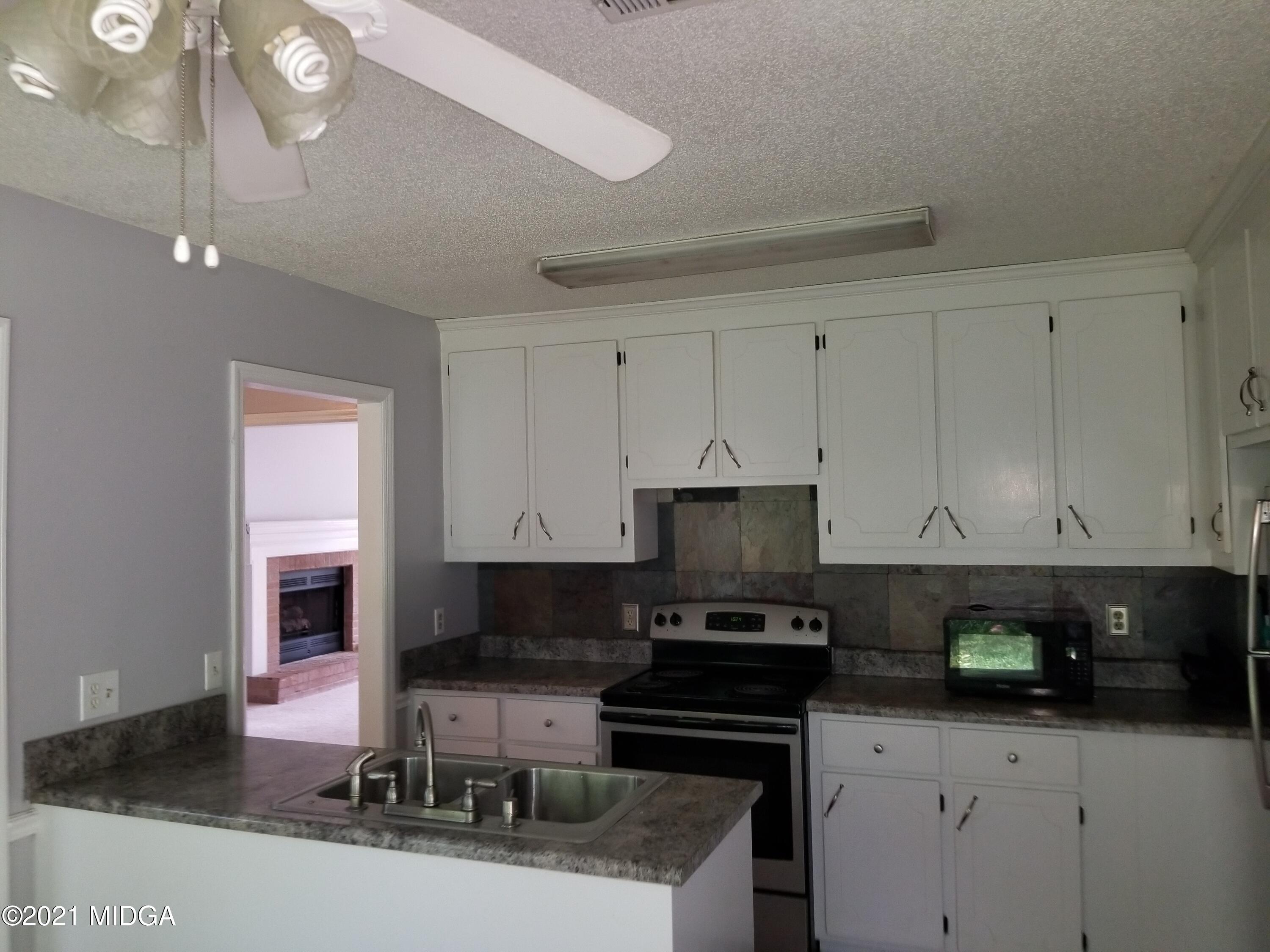 117 Chadwick Drive Macon, GA 31210 - Photo 7 of 8 a kitchen with granite countertop a stove and a white cabinets