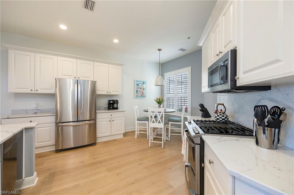 9288 Grassi Way, Unit 102 Naples, FL 34114 - Photo 12 of 37 Kitchen with stainless steel appliances, white cabinetry, decorative light fixtures, light stone countertops, and recessed lighting