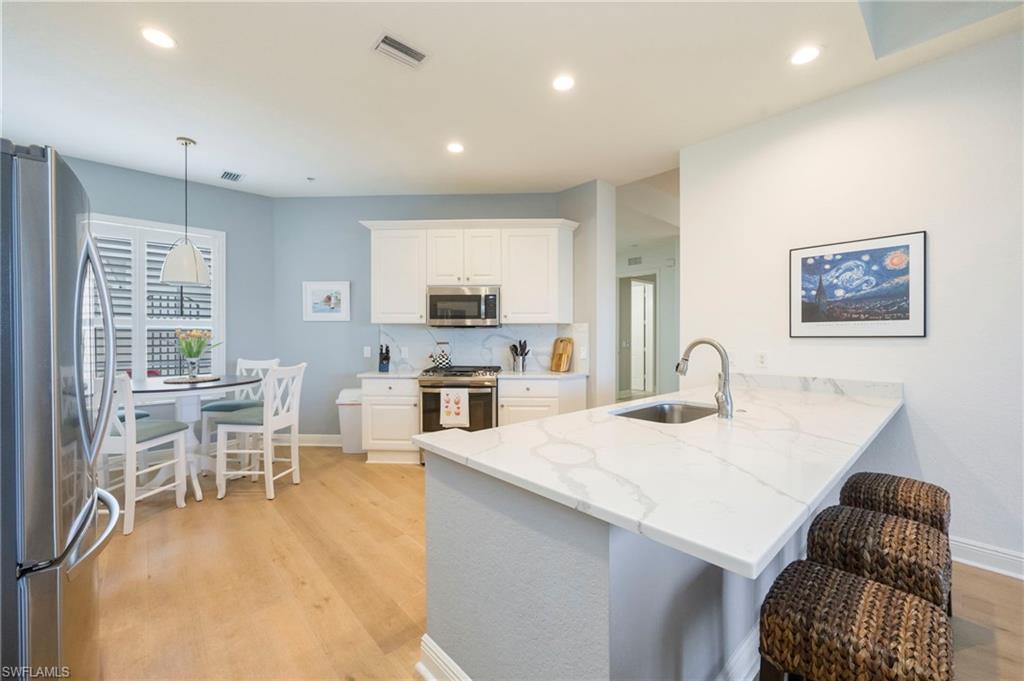 9288 Grassi Way, Unit 102 Naples, FL 34114 - Photo 13 of 37 a kitchen with stainless steel appliances kitchen island granite countertop a sink and cabinets