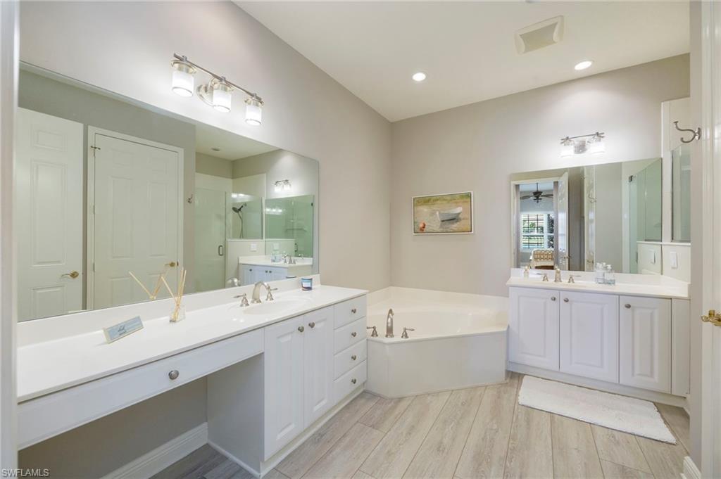 9288 Grassi Way, Unit 102 Naples, FL 34114 - Photo 16 of 37 Bathroom with a stall shower, a bath, two vanities, light wood-type flooring, and ceiling fan