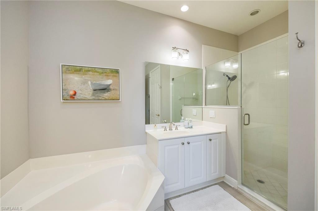 9288 Grassi Way, Unit 102 Naples, FL 34114 - Photo 17 of 37 Bathroom featuring a shower stall, a bath, and vanity