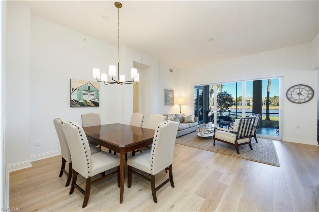 9288 Grassi Way, Unit 102 Naples, FL 34114 - Photo 6 of 37 a dining room with furniture a chandelier and wooden floor