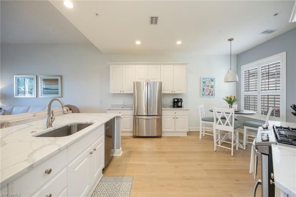 9288 Grassi Way, Unit 102 Naples, FL 34114 - Photo 10 of 37 Kitchen featuring white cabinets, light stone countertops, stainless steel appliances, healthy amount of natural light, and recessed lighting