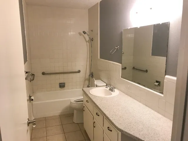 a bathroom with a granite countertop sink toilet and shower