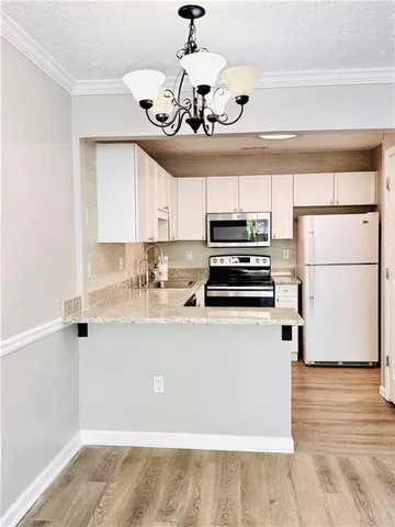 a kitchen with a refrigerator a stove cabinets and wooden floor