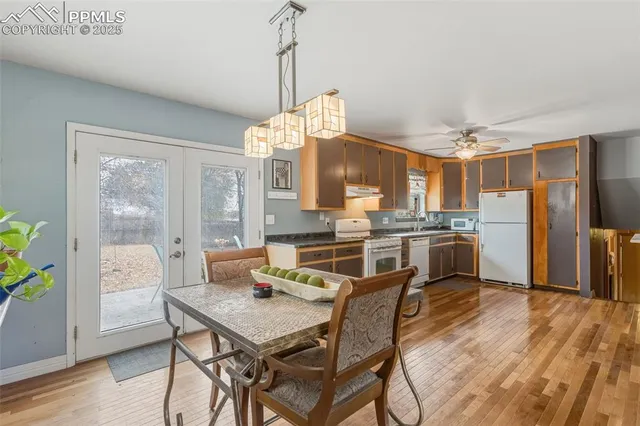 a kitchen with stainless steel appliances a dining table chairs and wooden floor