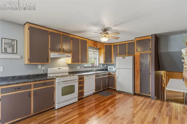 a kitchen with stainless steel appliances granite countertop a stove top oven a refrigerator cabinets and wooden floor